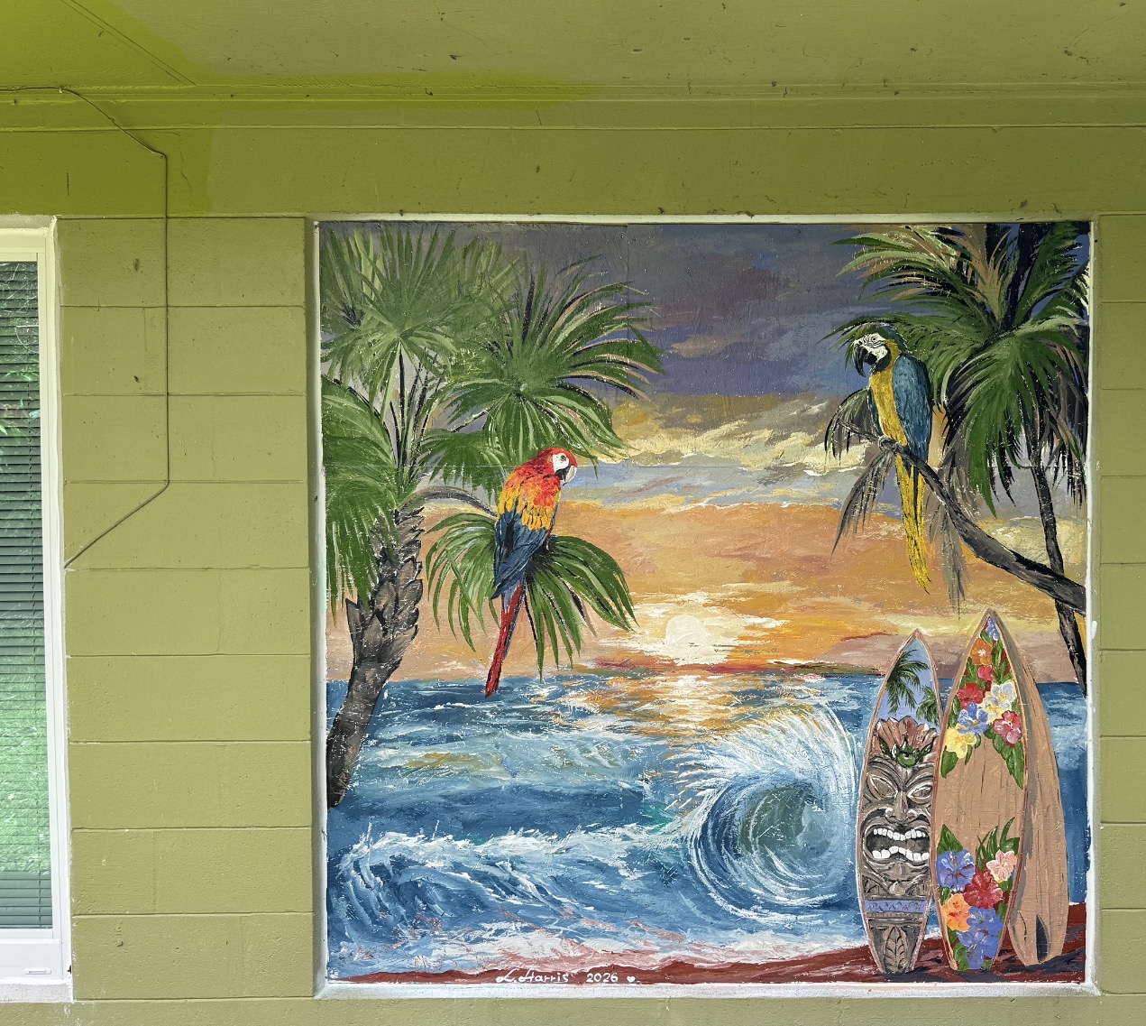 An exterior mural with ocean waves, parrots, palm trees, surfboards, and sunset colors.